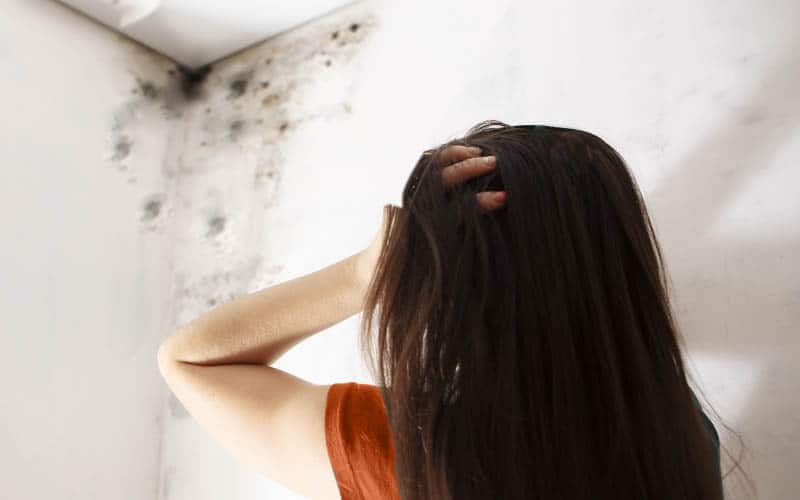 Mulher desesperada com marcas de infiltrações na parede